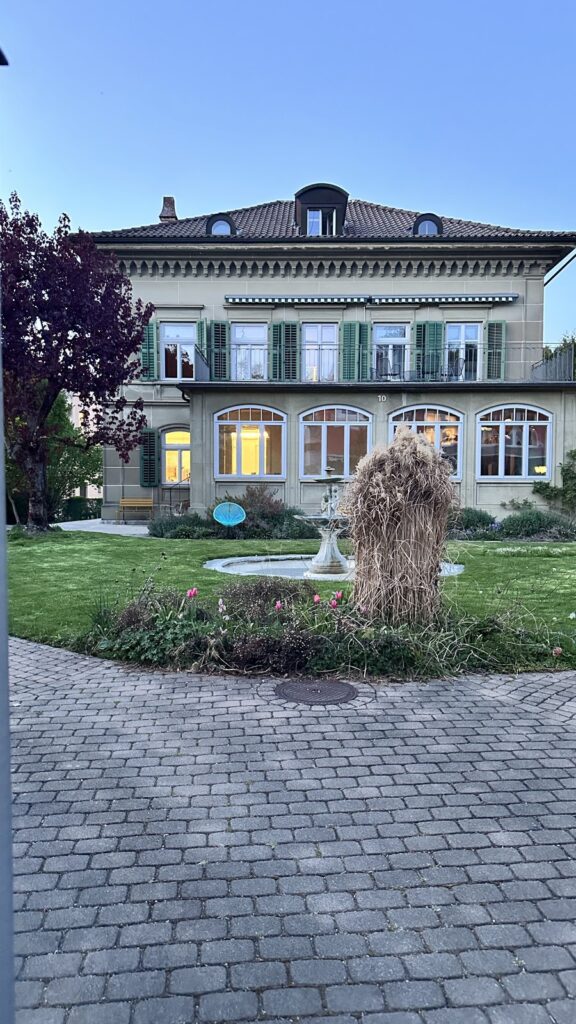 Villa Magnolia in der Abenddämmerung mit beleuchteten Fenstern und Garten